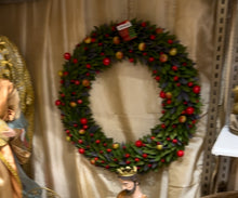 Decorative Christmas wreath with red and gold ornaments on a neutral background